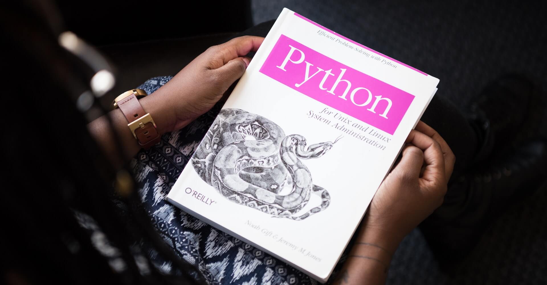 PyQuant News - a person holding a python programming book